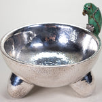 A silver-plated molcajete bowl with a malachite gem figure in the shape of a parrot.