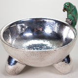 A silver-plated molcajete bowl with a malachite gem figure in the shape of a parrot.
