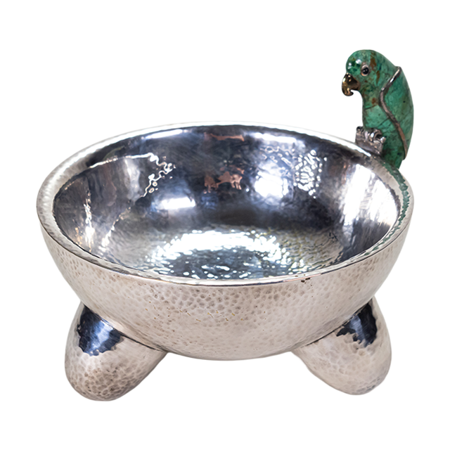 A silver-plated molcajete bowl with a malachite gem figure in the shape of a parrot.