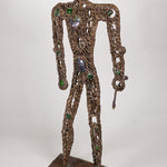 A brass metal sculpture of a hunter with gemstones and tiny figures ornate on it's body, holding a spear.
