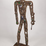 A brass metal sculpture of a hunter with gemstones and tiny figures ornate on it's body, holding a spear.