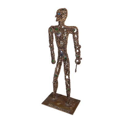 A brass metal sculpture of a hunter with gemstones and tiny figures ornate on it's body, holding a spear.