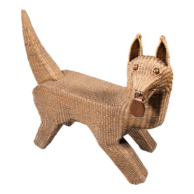 A seagrass woven over wire piece in the shape of a dog, looking to it's side with metal tongue hanging out.