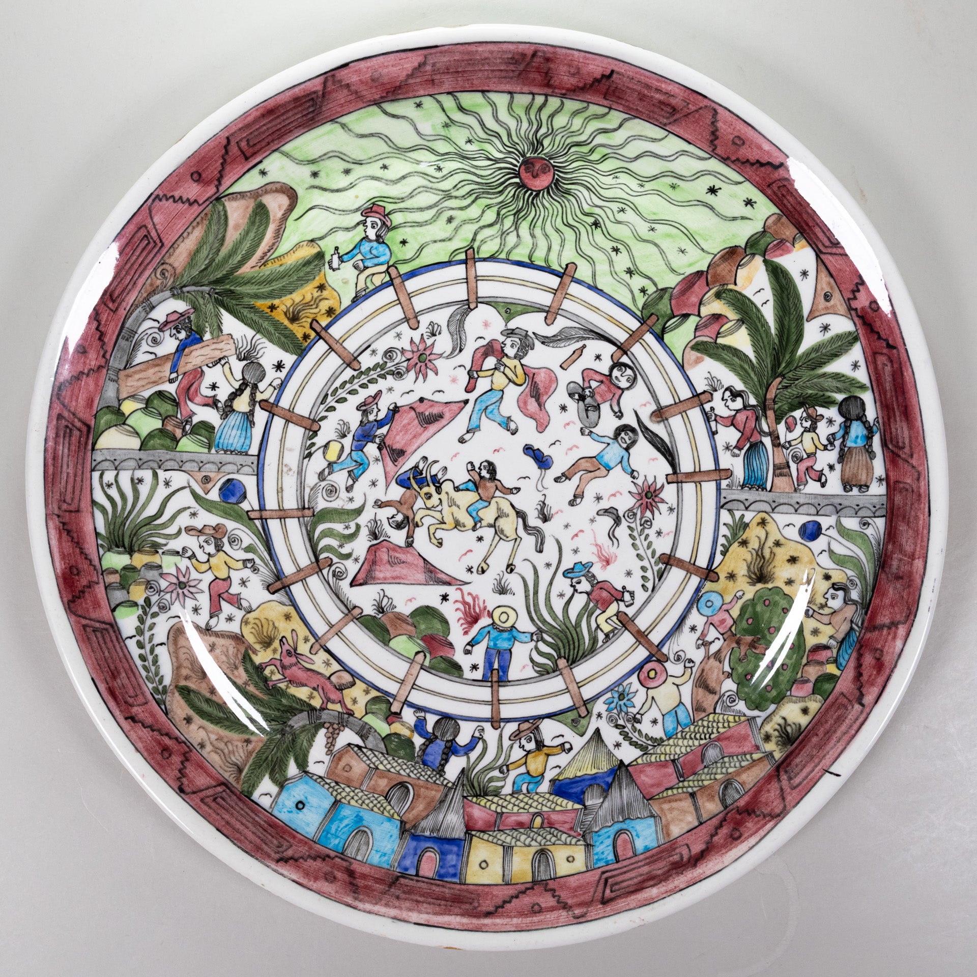 A round ceramic plate with artwork of bull fight scene in the center and spectators all around.
