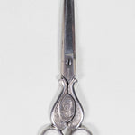 Silver sewing scissors decorated with a plant and floral design, with President Porfirio Diaz's bust.