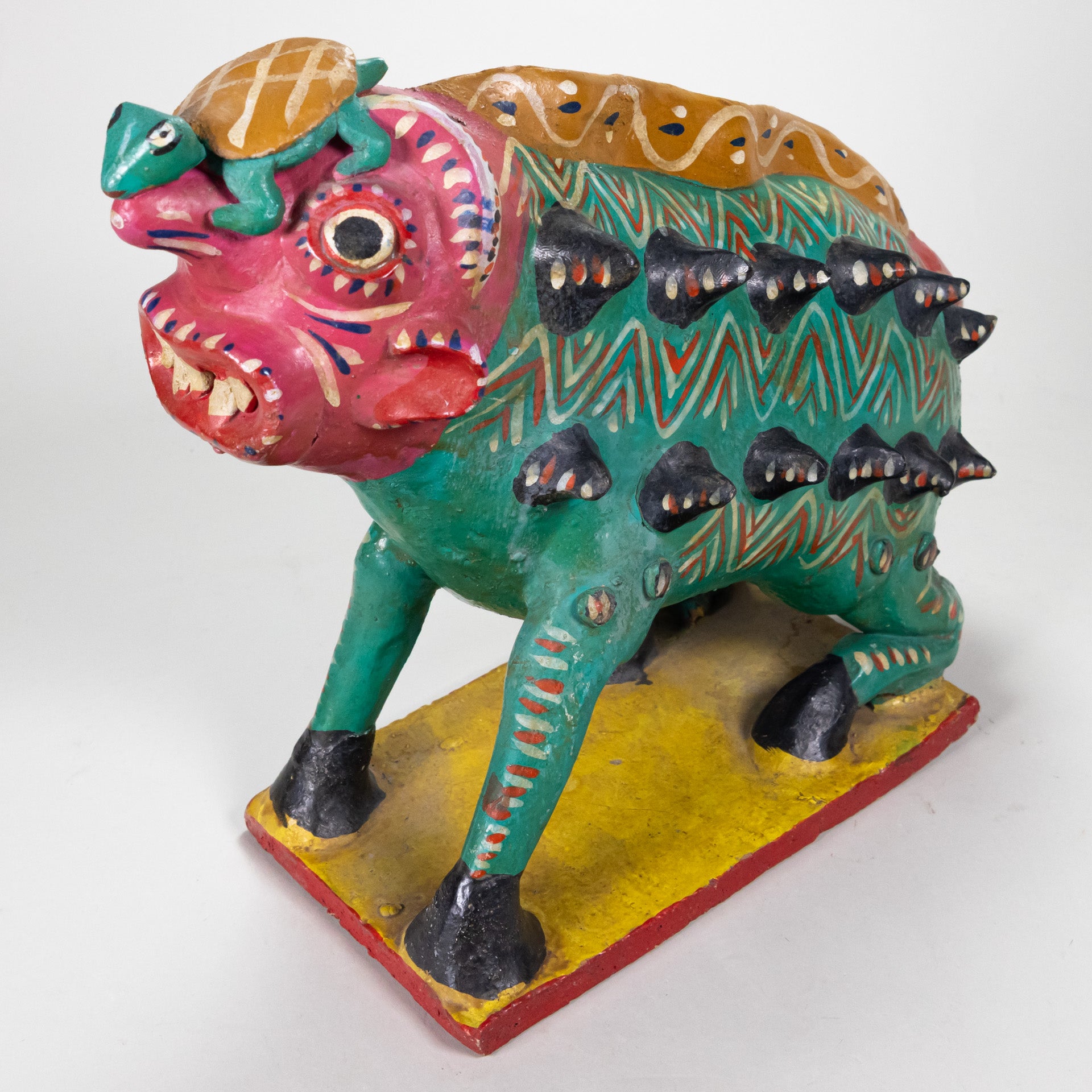 Nagual pottery figure with a human-like face, sharp teeth, and a green animal body with spikes coming out on the side, hooves, and a turtle on its head.