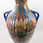 Large pottery vase with two blue handles and a floral design over orange color.