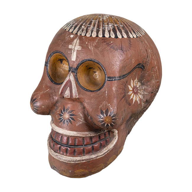 Ceramic piece in the shape of a calavera (skull) with hand-painted details of glasses, flowers and a cross on the forehead.